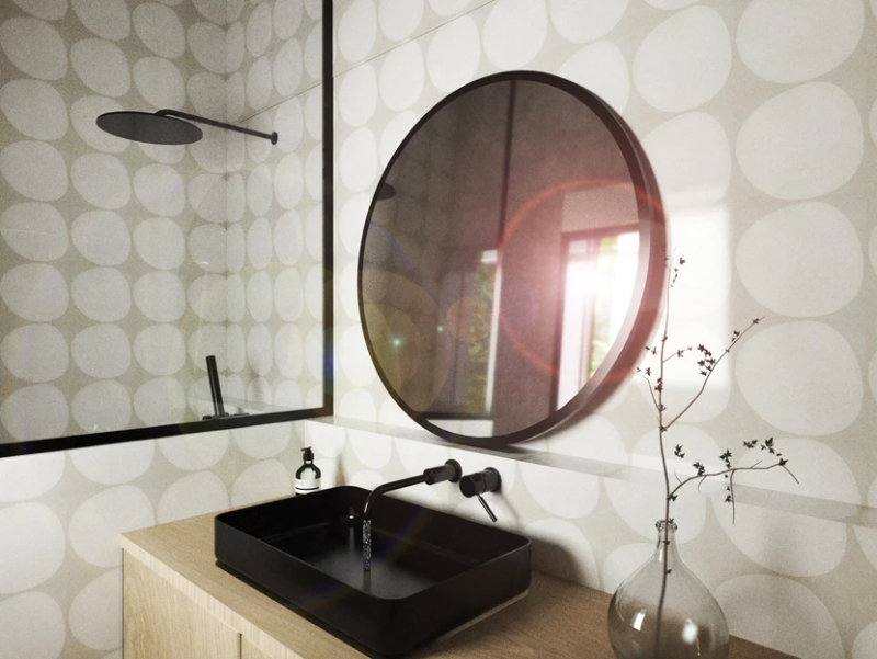 Maddona bathroom  with a black round mirror, a rectangular black washbasin and we can also see a black head shower rain.