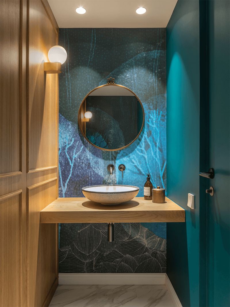 bathroom with blue wall,white sink and wooden vanity, circular wall mirror