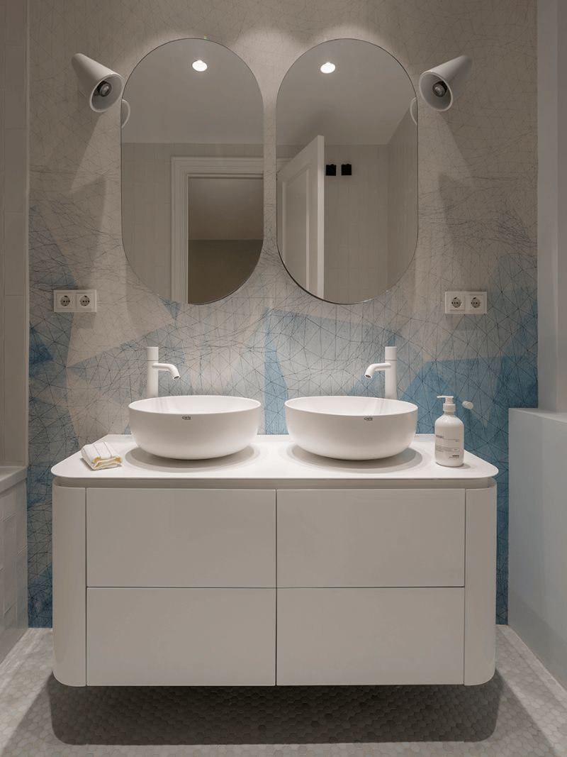 bathroom with two white sinks, white vanity and oval mirrors
