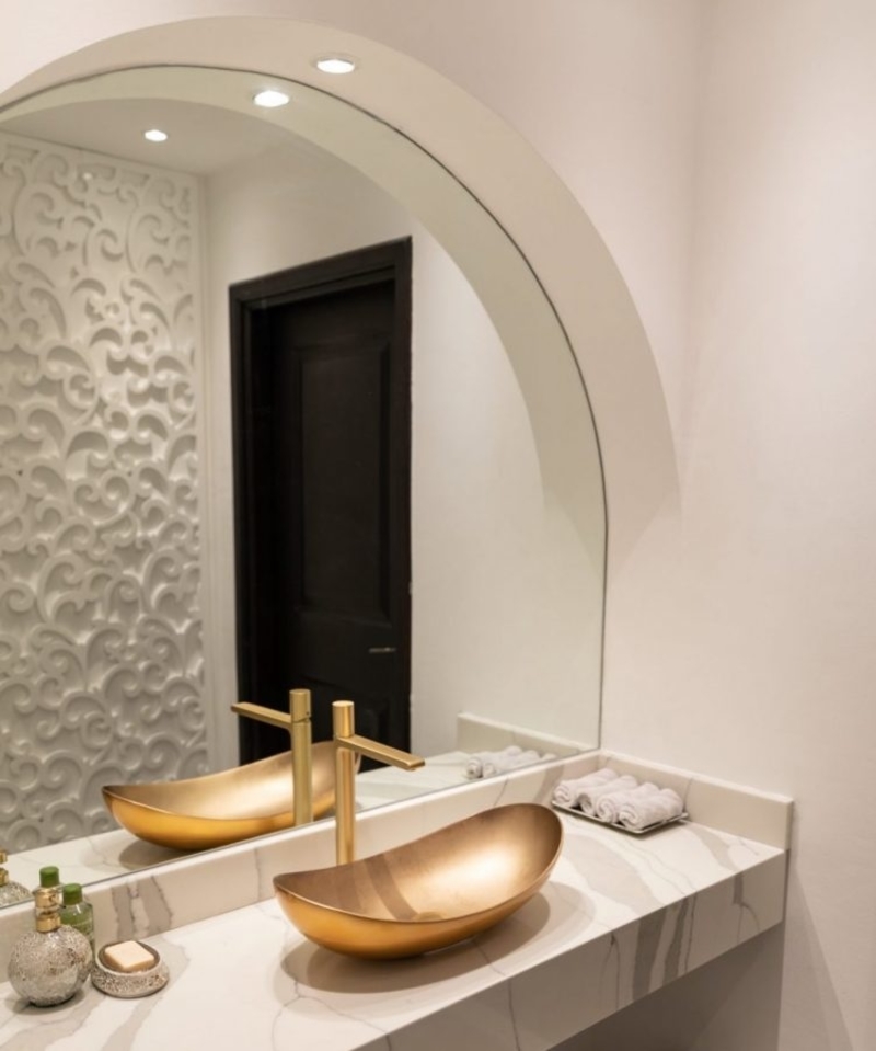 A bathroom furnished with a custom washbasin and a brass vessel sink.