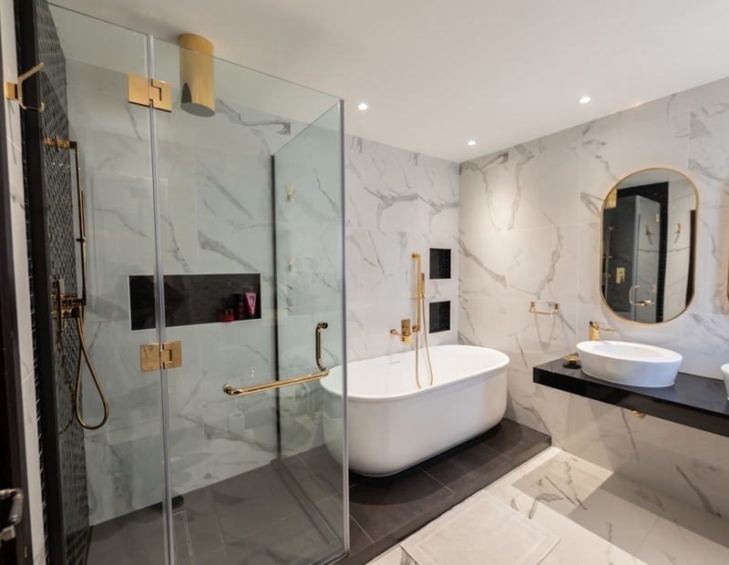 A bathroom with gold details, completed with a custom bathtub, a vessel sink and shower.