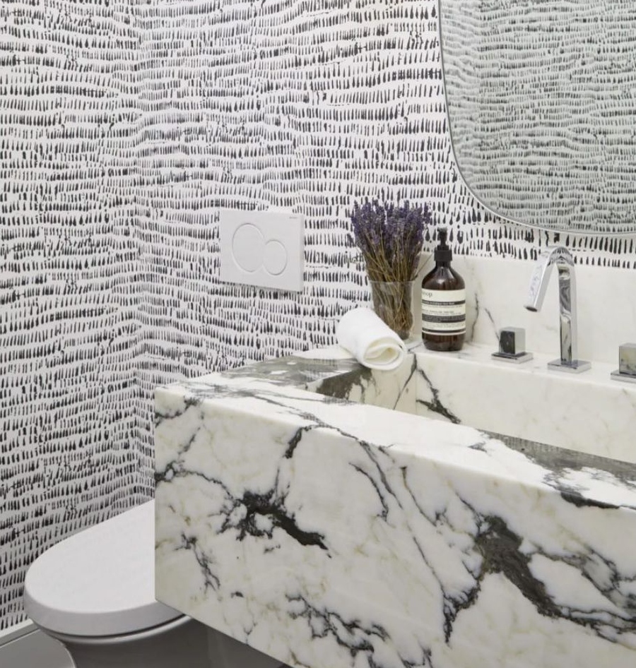 Bathroom designs ideas by Dvira Interiors. The walls were decorated with a chic and textured wallpaper that came with pops of black and white patterns. The wallpaper gives the space a more casual and bold feel!⁠ The floating stone vanity is a true feature in this space and creates a beautiful yet bold statement.⁠