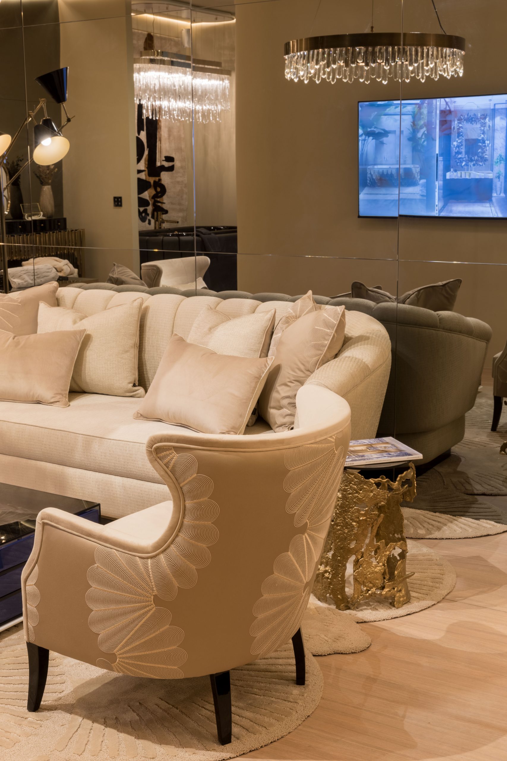 Home Society luxury curved sofa with gold sculptural side table and crystal chandelier at iSaloni 2026