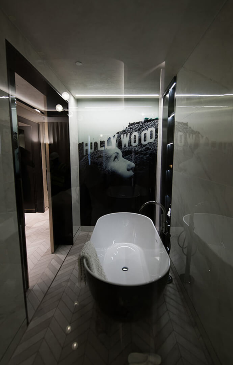 A bathroom decorated with white marble walls furnished with a custom bathtub.