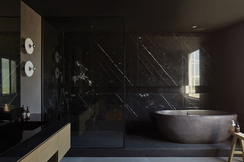 Bathroom with black marble walls furnished with a custom bathtub.