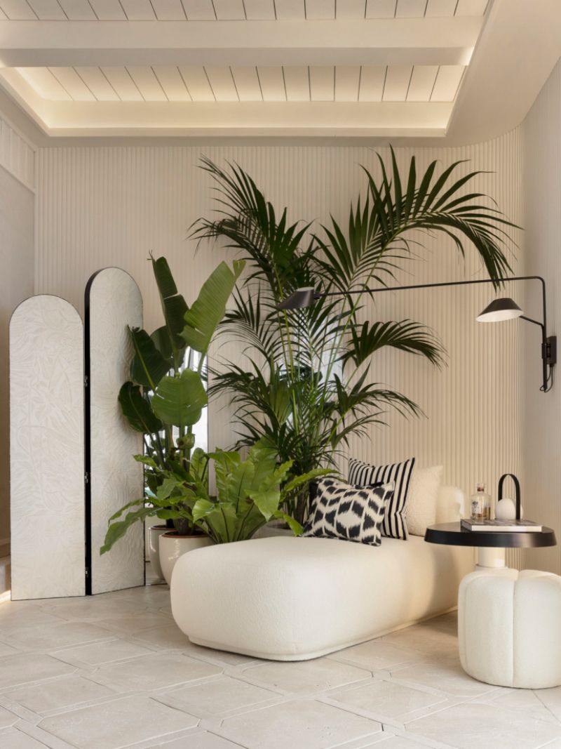 bathtub by marisa gallo with white ottoman and black side table, plants
