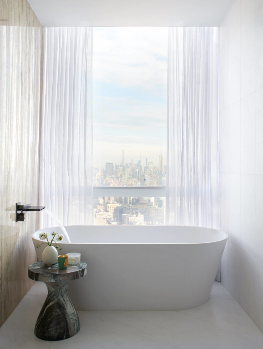 Neutral bathroom with freestanding bathtub with looks over New York by Nicole Fuller Interiors - 111 Murray Street Project