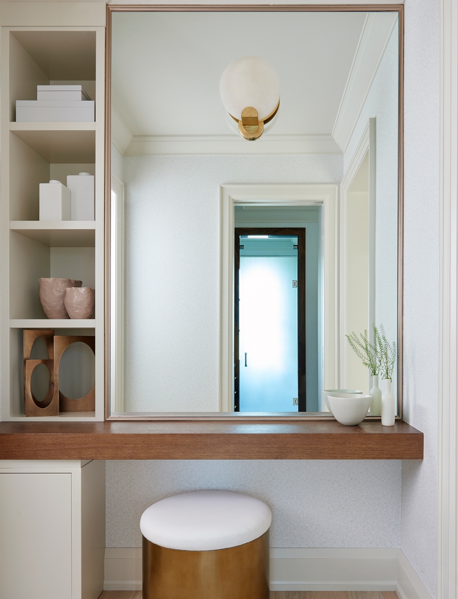 Bathroom design ideas from Stacey Cohen Design. This corner of the bathroom has a wood table, a mirror, shelves in white, and a white stool.