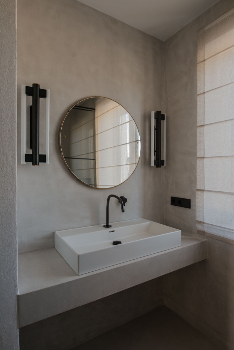 bathroom by Ibiza Interiors with white sink and round mirror