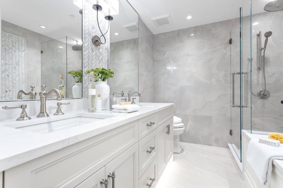 Ideas to decorate the bathroom by Beyond Beige. This master bathroom with grey walls has white sinks and two mirrors.